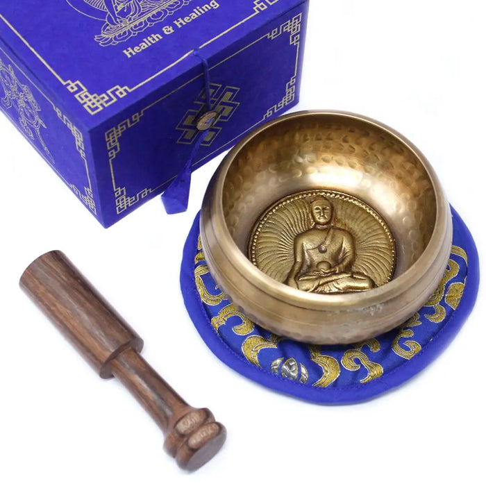 Golden medicine buddha singing bowl with hammered texture and embossed buddha on blue embroidered mat 10cm