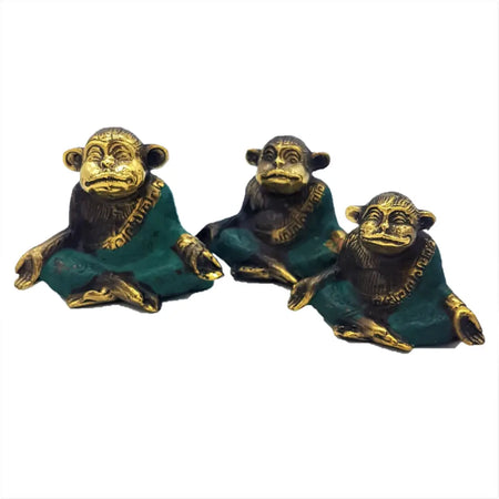 Three brass monkeys with green patina robes and gold trim seated in different meditating brass poses