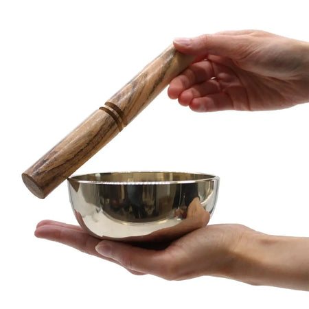 Medium brass singing bowl made of shiny silver metal with a wooden mallet and two brass-colored rings