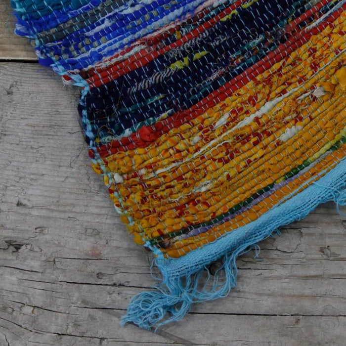 Medium rag rug in blues reds yellows and oranges with frayed edges made from handwoven textured rag rugs material