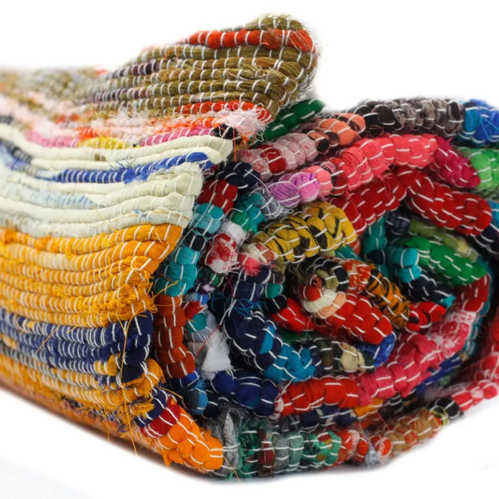 Medium natural rag rug with vibrant multicolored woven stripes and frayed edges handcrafted from fabric strips
