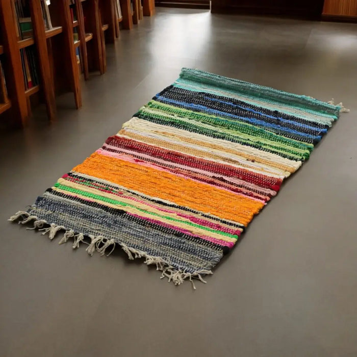Medium rag rug with handwoven stripes and frayed edges in vibrant rainbow colours made from recycled fabric fibers
