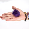 A deep purple amethyst crystal point with a faceted geometric shape resting in an open palm weighing 139g approx