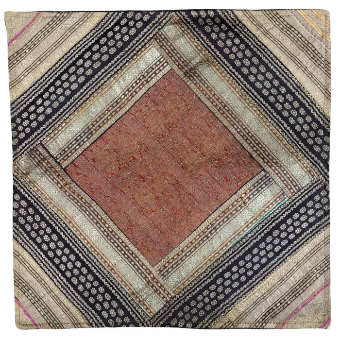 A patchwork cushion cover with a rust diamond and metallic thread details in black beige silver and muted tones