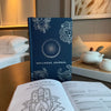 Midnight blue wellness journal with deep blue textured cover and silver foil stamped floral and zodiac designs