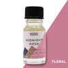 A clear glass bottle with black ribbed cap holds pale yellow midnight rose fragrance oil with allergen declarations label