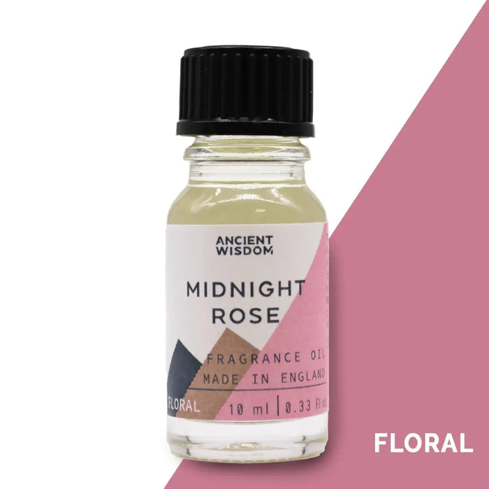 A clear glass bottle with black ribbed cap holds pale yellow midnight rose fragrance oil with allergen declarations label