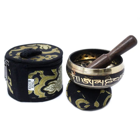 Black and gold mini singing bowl with engraved sanskrit script and wooden mallet in a mini singing bowl gift set