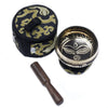 Black and gold mini singing bowl with intricate face design, wooden mallet, and embroidered carrying case