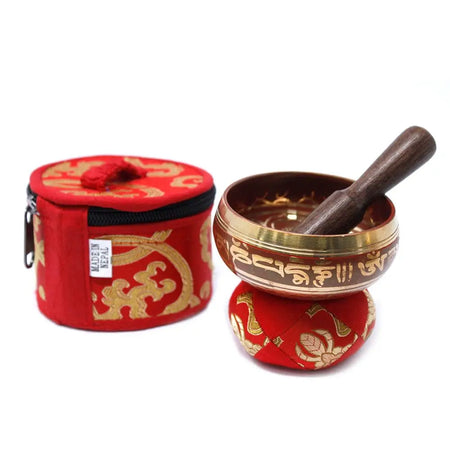 Red and gold embroidered carrying case with a brass mini singing bowl featuring intricate golden script along its rim