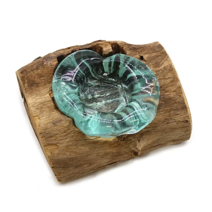 A translucent teal glass gamal wood tealight holder with swirling black patterns on a rustic wooden base