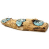 A rustic gamal wood driftwood candle holder with three light blue glass tealight cups embedded in the textured surface