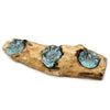 A rustic triple tealight holder with translucent teal glass bowls on a gamal wood driftwood base with etched designs