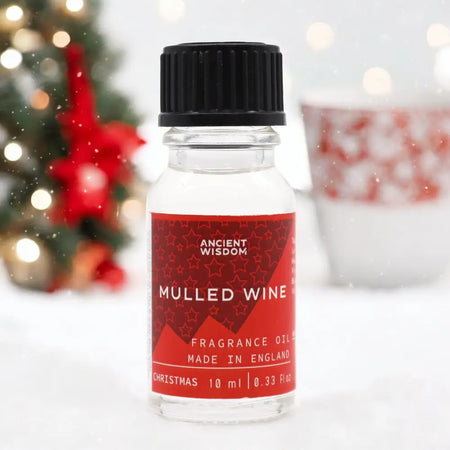 A clear glass bottle of ancient wisdom mulled wine fragrance oil with black cap and red label for christmas use