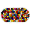 A multi-colour felt ball centre mat oval made of wool with vibrant round balls in a patchwork pattern