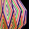A multi-coloured origami light shade with bold red green and purple striped diamond patterns on cream paper