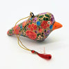 A multi floral hand painted papier mache bird bauble with red green blue and purple patterns and a bright orange beak