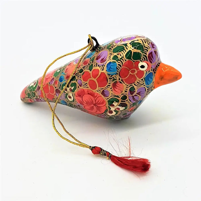 A multi floral hand painted papier mache bird bauble with red green blue and purple patterns and a bright orange beak
