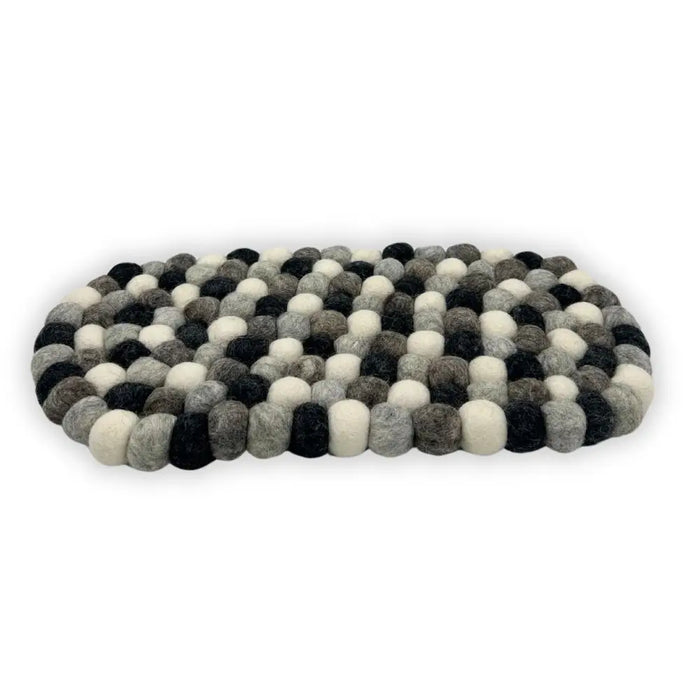 An oval-shaped multi-grey felt ball centre mat made of tightly woven fluffy wool balls in black white and grey shades