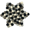 A star-shaped multi-grey felt ball centre mat made of fluffy wool balls in black white and shades of grey