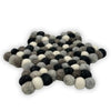 A star-shaped multi-grey felt ball centre mat made of fluffy wool balls in black white and shades of grey