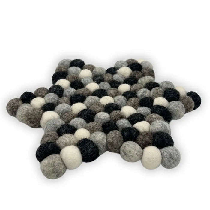 A star-shaped multi-grey felt ball centre mat made of fluffy wool balls in black white and shades of grey