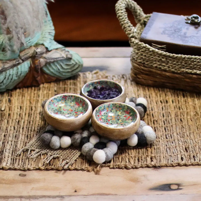 Three ceramic bowls with speckled green interiors on a multi-grey felt ball centre mat star design