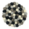 Round coasters made of interlocking black white and grey wool felt balls in a set of four