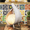 A rustic teardrop-shaped natural coconut lamp with greywash wrapover and a warm glowing wood interior light