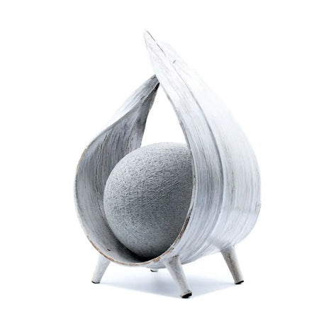 Natural coconut lamp with gray textured sphere inside a whitewash distressed shell on three slender legs