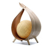 A natural coconut lamp with a warm golden spherical light inside a light wood curved frame with three slim legs
