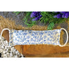 A cream cotton heating bag with blue floral pattern and braided handles filled with natural wheat for warmth