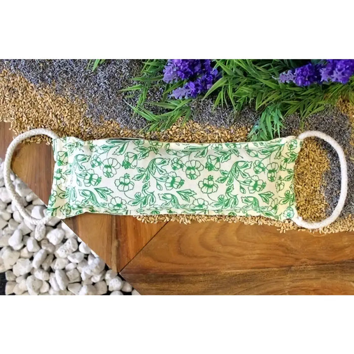 A rectangular cream cotton heating bag with wheat filling green floral pattern and white rope handles
