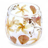 A clear glass candle holder with preserved yellow and brown flowers made from recycled glass in a straight design