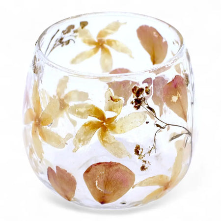 A clear glass candle holder with preserved yellow and brown flowers made from recycled glass in a straight design