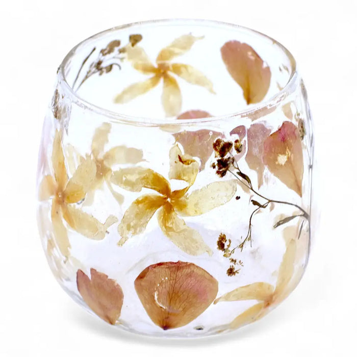 A clear glass candle holder with preserved yellow and brown flowers made from recycled glass in a straight design