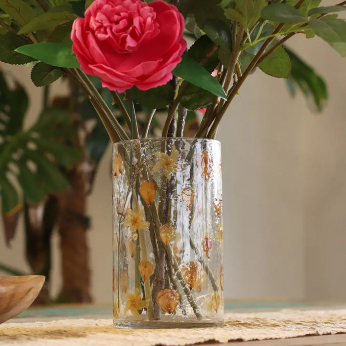 Clear glass recycled glass candle holder vase with embossed gold floral patterns holding a pink rose