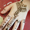 A hand with intricate brown henna paste geometric designs using natural NEHA Mehandi henna cone