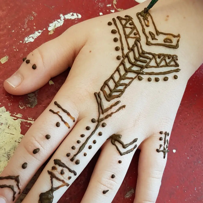A hand with intricate brown henna paste geometric designs using natural NEHA Mehandi henna cone