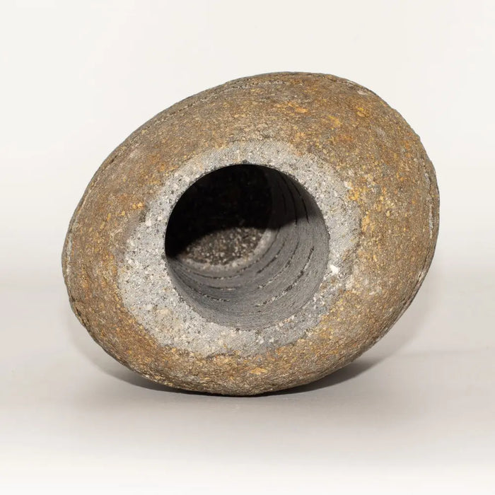 Rough-textured earth-toned ceramic candle holder with wide mouth and internal rings resembling a standing stone design