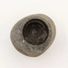 A smooth dark gray natural riverstone pestle mortar with a rounded shape and hollowed center for grinding use