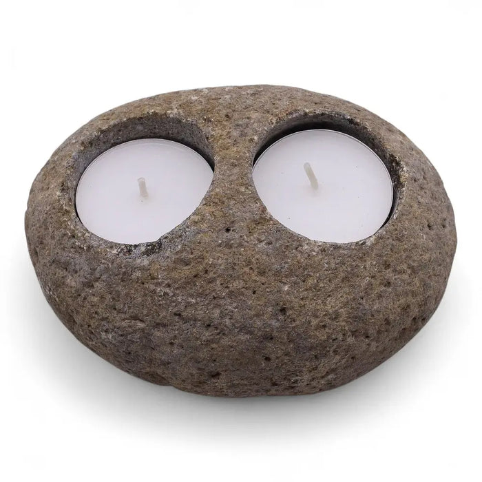 Natural riverstone tealight holder made of dark gray stone with two circular indentations holding white tealights