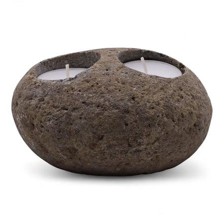 Natural riverstone tealight holder in dark brown with rough texture and two white tealights in circular indentations
