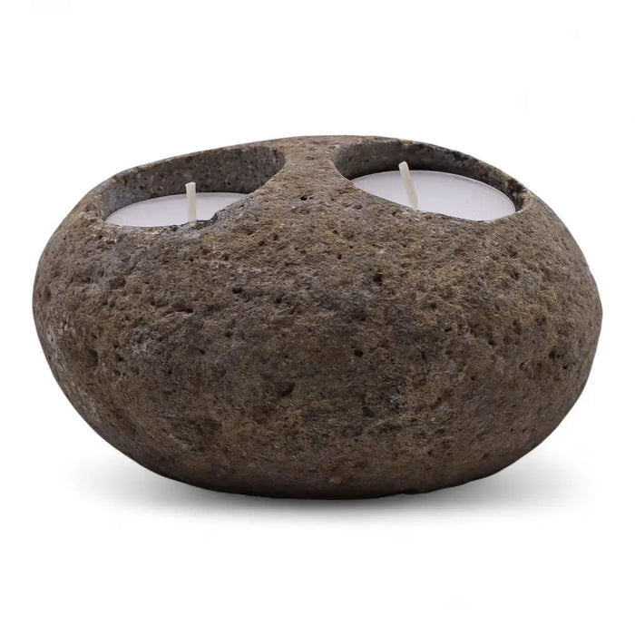 Natural riverstone tealight holder in dark brown with rough texture and two white tealights in circular indentations
