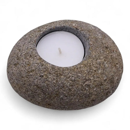 Rounded gray riverstone tealight holder with smooth textured surface and circular indentation holding white candle