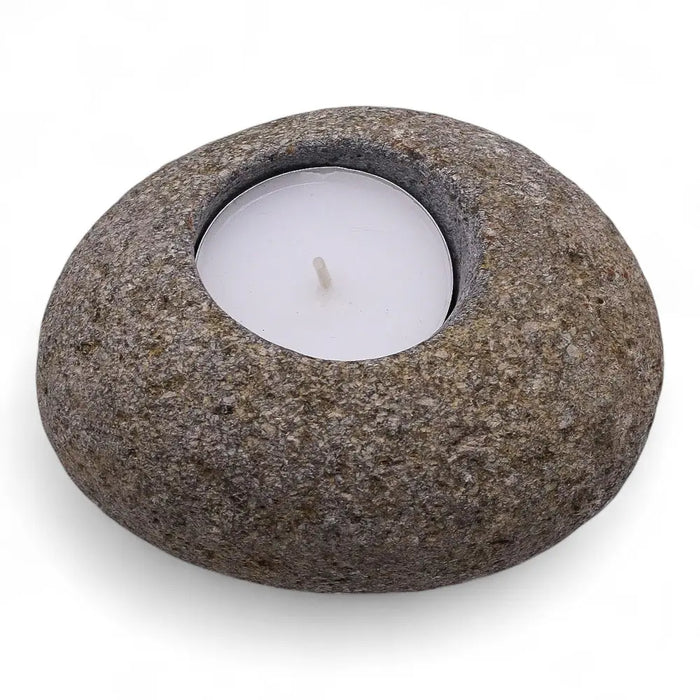 Rounded gray riverstone tealight holder with smooth textured surface and circular indentation holding white candle