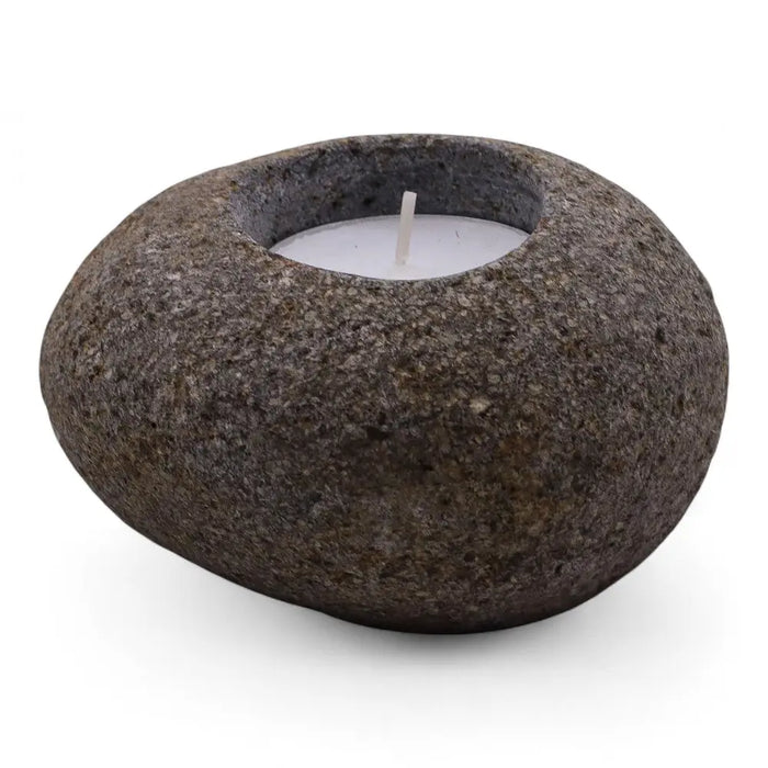 Rounded dark gray natural riverstone tealight holder with smooth texture and central opening holding white candle