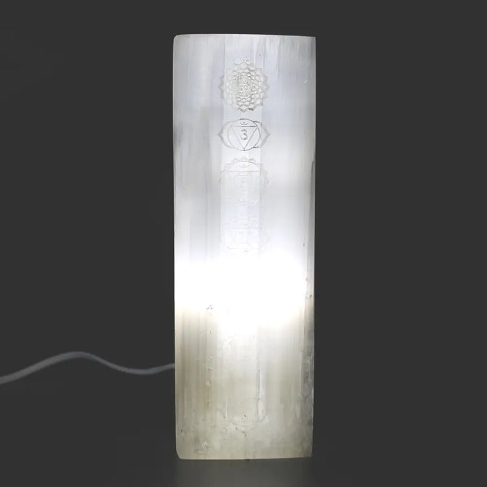 Natural selenite block lamp with etched chakra symbols glowing softly inside a translucent rectangular crystal block