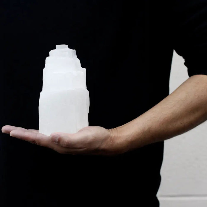 A translucent white selenite tower lamp with a stepped pyramid design and smooth polished facets measuring 15cm