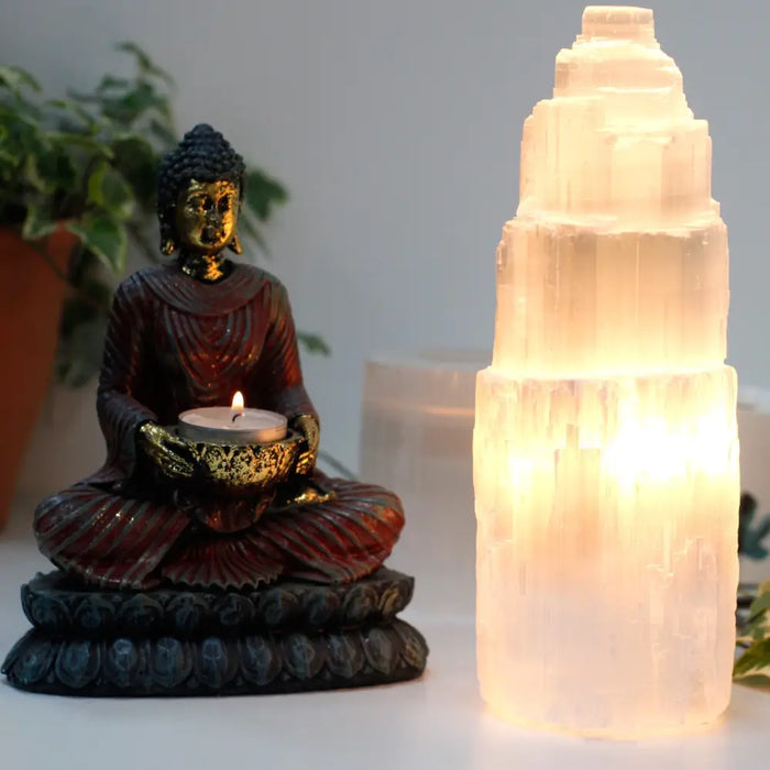 A translucent natural selenite tower lamp with a tiered geometric design glowing softly available in three sizes